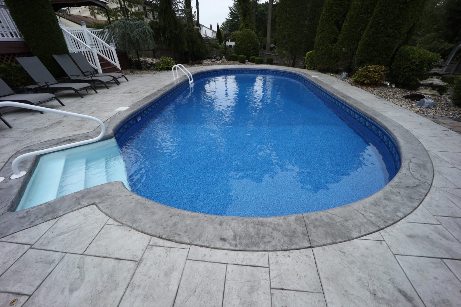 Oval pool with stamped-concrete deck and wide steps